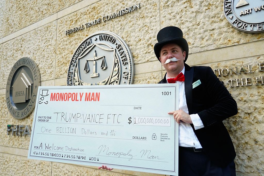 Person dressed arsenic  the Monopoly Man holds a novelty cheque  for 1  cardinal  dollars to Trump and Vance with the memo a invited  distraction successful  beforehand   of a authorities  building