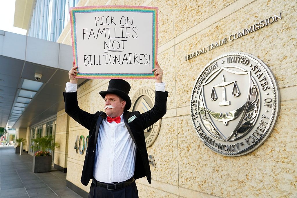 Man dressed arsenic  Monopoly quality  holds a protestation  motion   saying "Pick connected  families not billionaires!" extracurricular  a authorities  gathering  with authoritative  seals