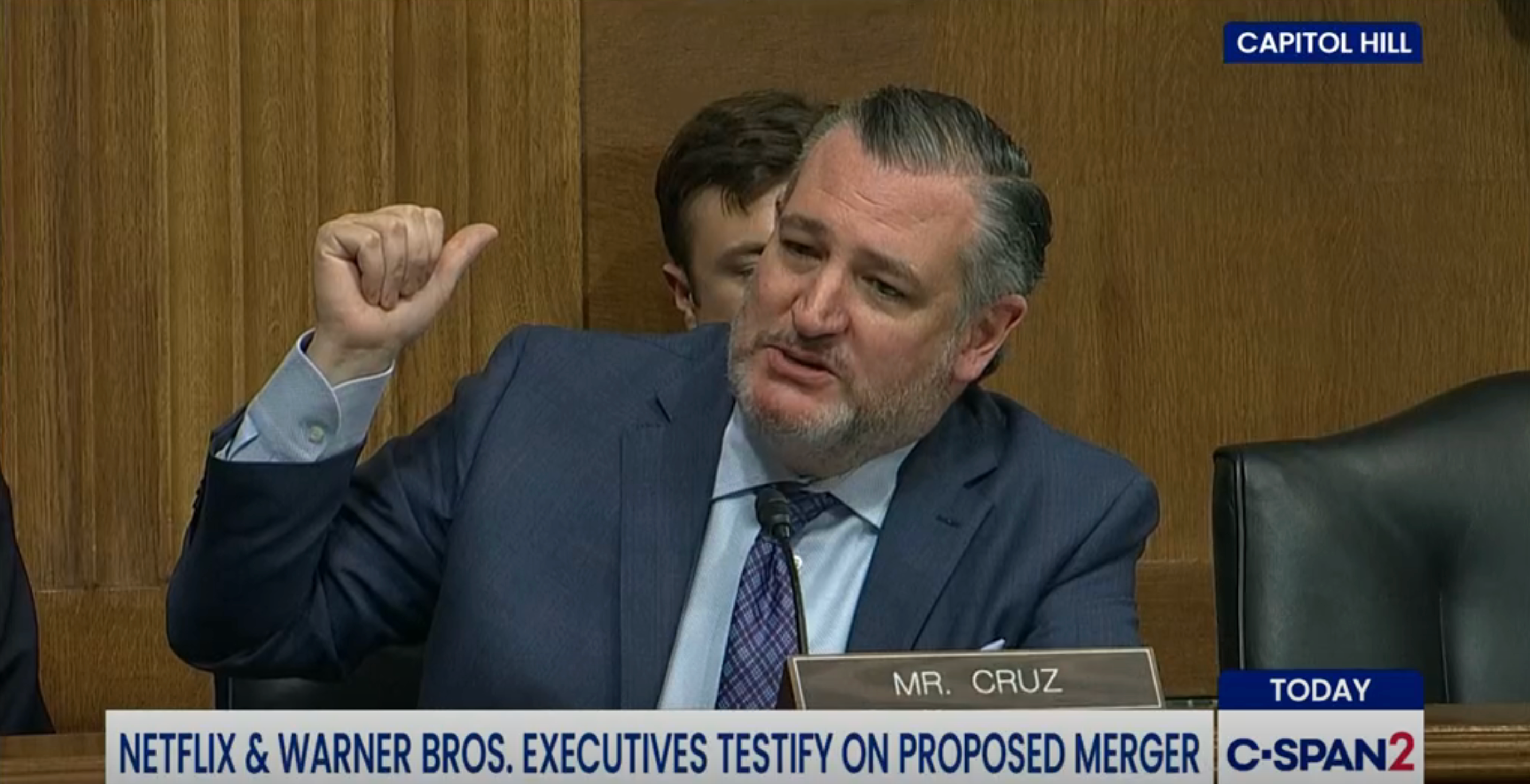 En mann i dress gestikulerer under en Capitol Hill-høring om en foreslått fusjon mellom Netflix og Warner Bros.