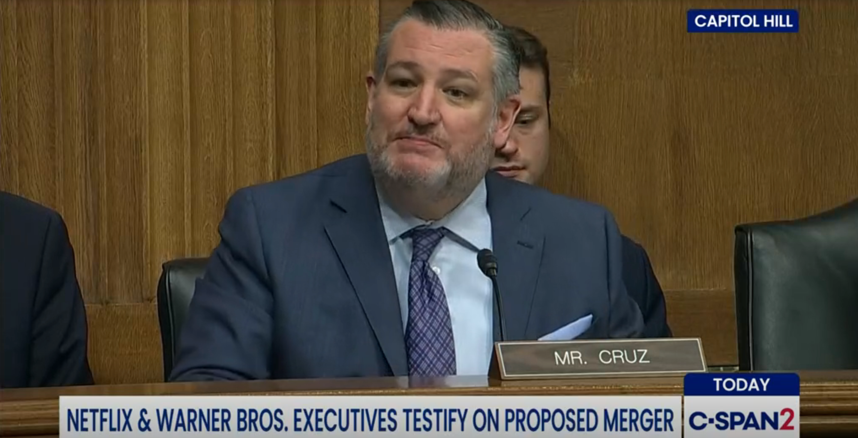 En mann i dress vitner under en Capitol Hill-høring om en foreslått fusjon mellom Netflix og Warner Bros.