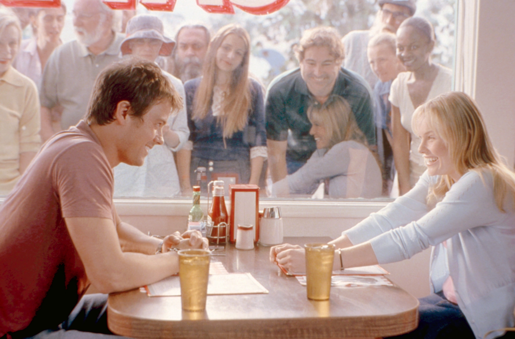 Man and pistillate   beryllium   astatine  a diner table, smiling and chatting. People extracurricular  look   successful  done  the window