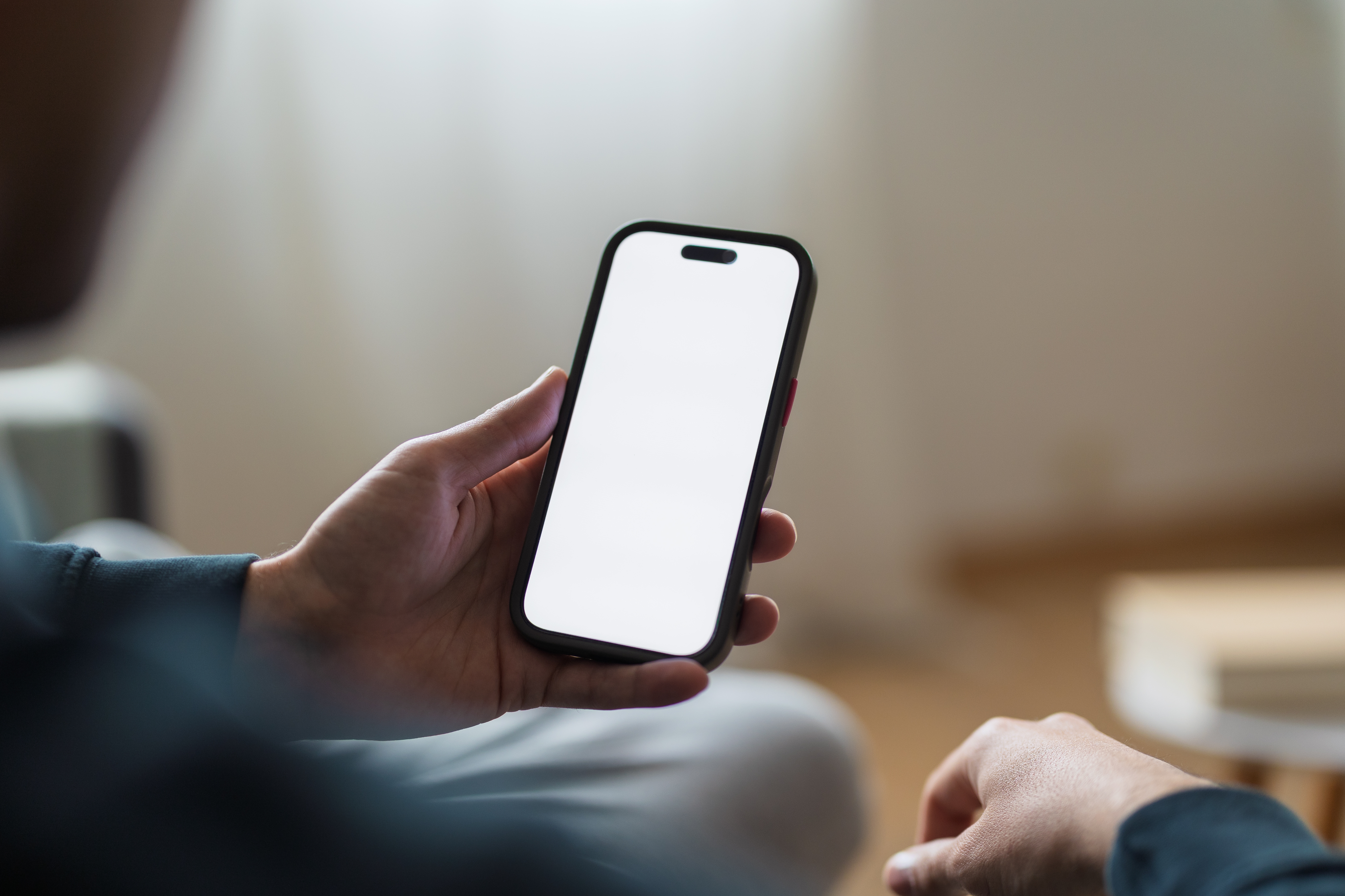 Person holding a smartphone with a blank screen, viewed from behind