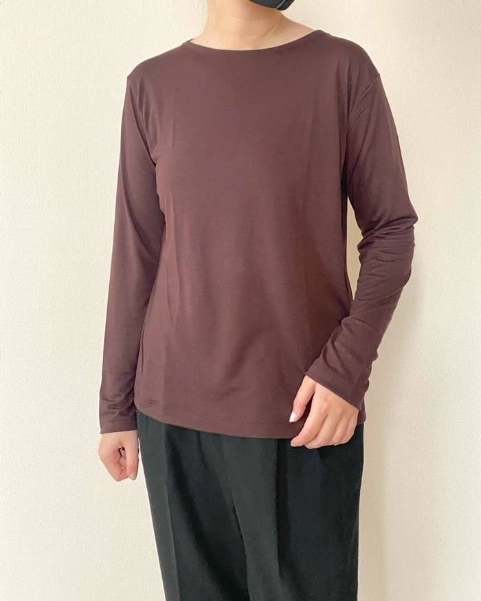 UNIQLO（ユニクロ）の「シアーT」長袖のシンプルなスタイルのトップスを着た女性が立っている。