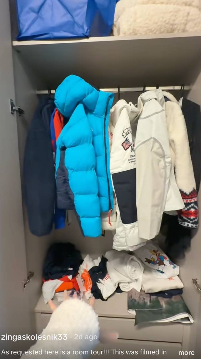 Open closet with assorted  jackets and coats hanging, immoderate   folded apparel  connected  the support  below