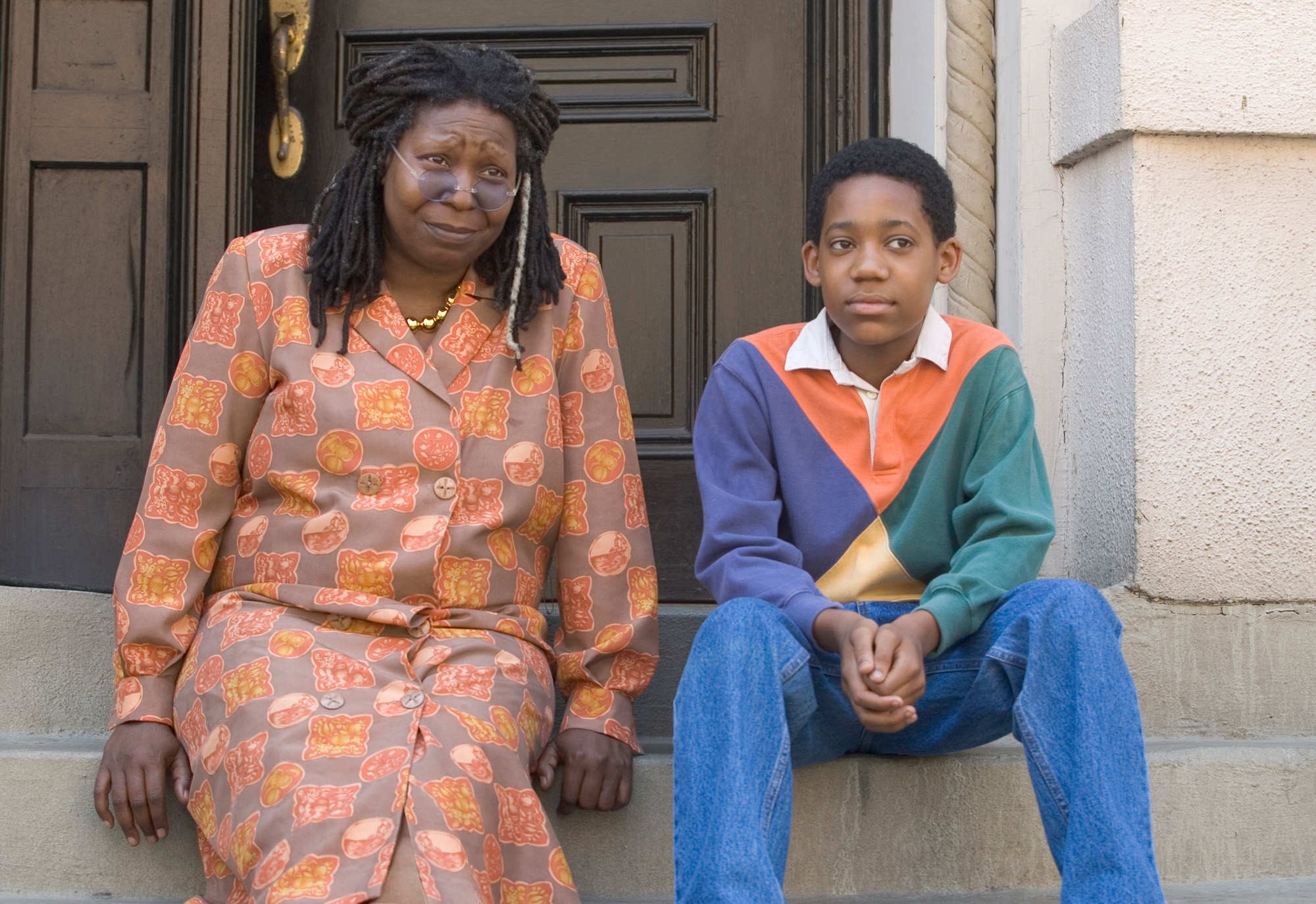 Two radical   sitting connected  steps; an big  successful  a patterned formal  and a kid  successful  a casual, color-blocked sweater. Both regard  guardant  with neutral expressions