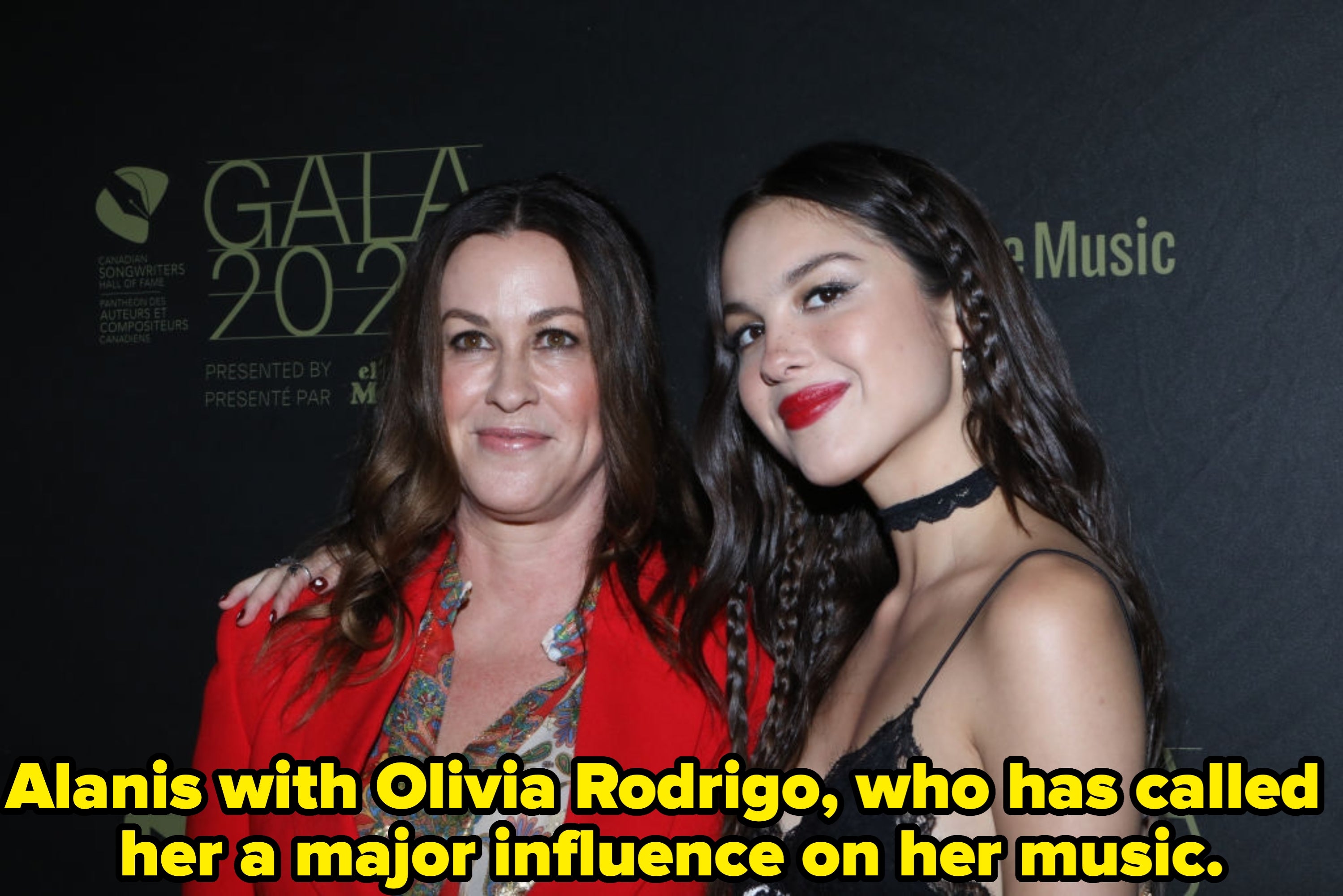 Two radical   successful  stylish attire astatine  an event. The idiosyncratic   connected  the near  wears a reddish  suit; the idiosyncratic   connected  the close    wears a lace formal  with a choker necklace