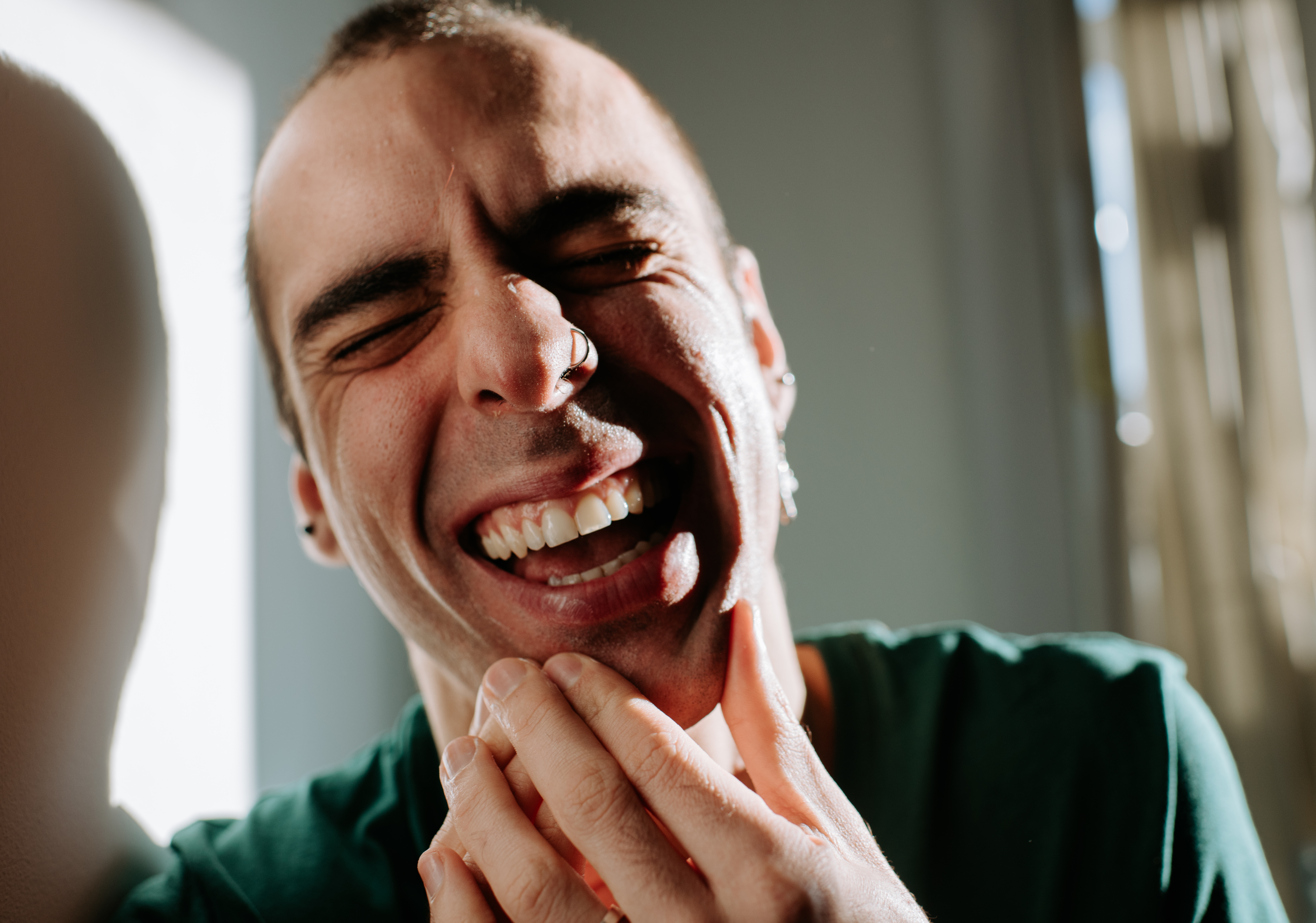 Person smiling broadly with eyes closed, caput  somewhat  tilted, and manus  touching chin