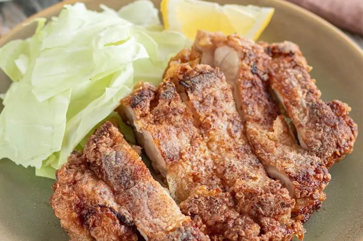 皿の上にあるサクサクに揚げたチキンカツとキャベツ、レモンのくし形切り。