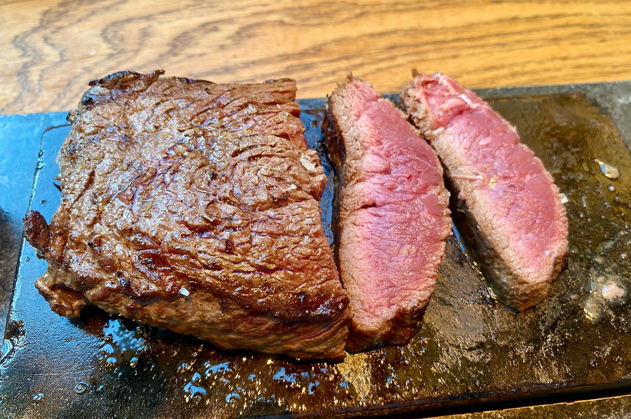 ステーキがカットされ、石板の上に置かれた様子。肉はジューシーで、焼き加減はレア。