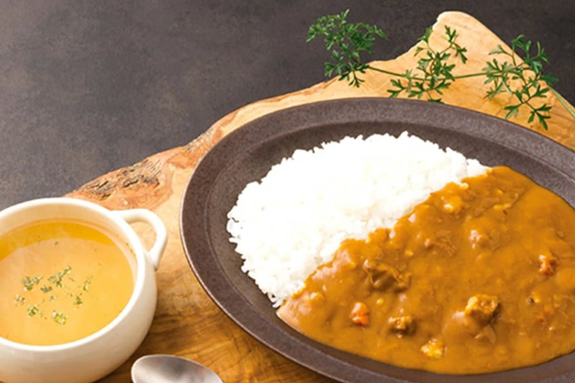 カレーライスとスープが木製トレイに乗っている。