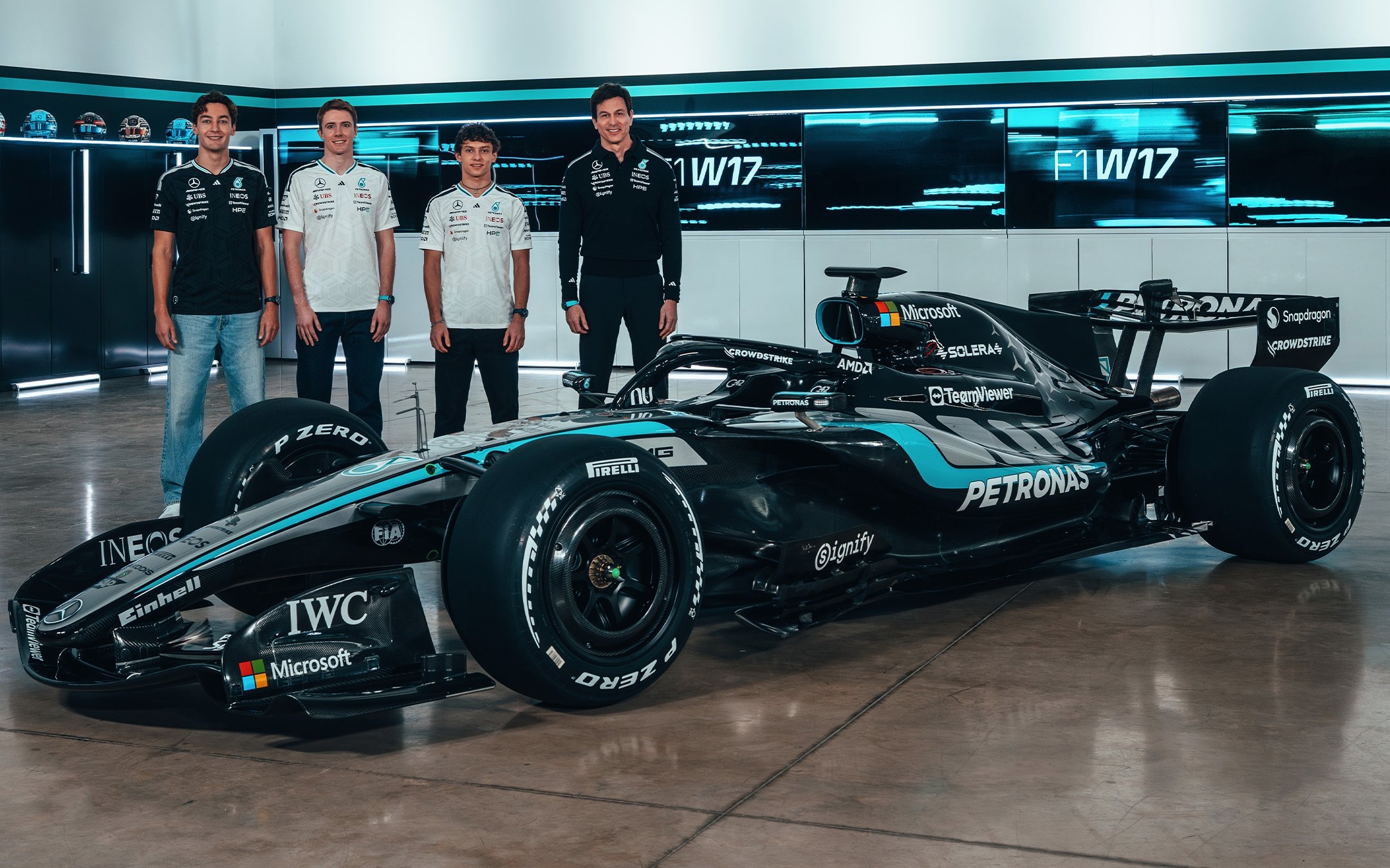 Four individuals stand beside a sleek Formula 1 car in a modern showroom