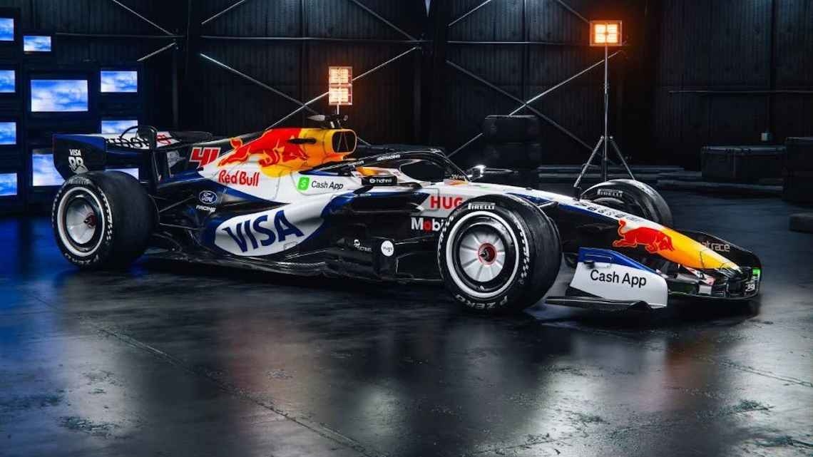 A Formula 1 race car with various sponsor logos displayed, parked in a dimly lit setting