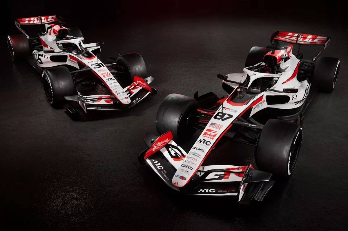 Two sleek Formula 1 cars with aerodynamic designs are showcased in a studio setting