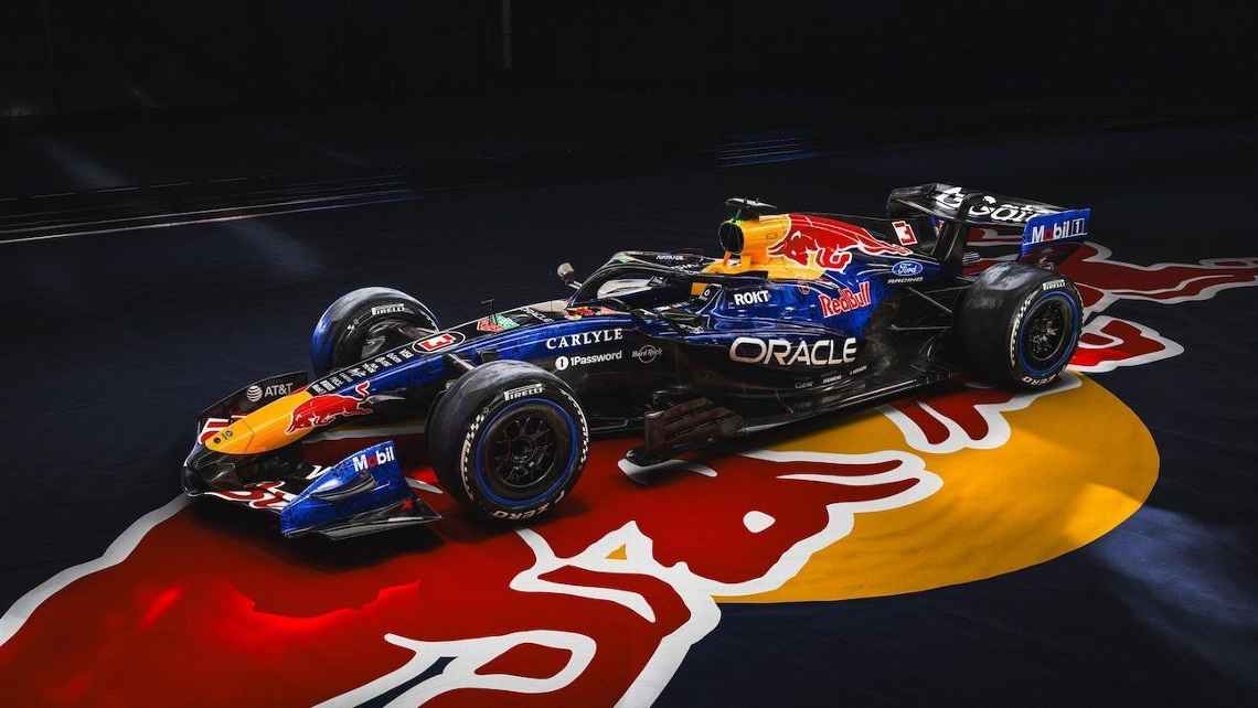 Race car with sponsor logos, including Red Bull and Oracle, parked on a Red Bull-themed floor