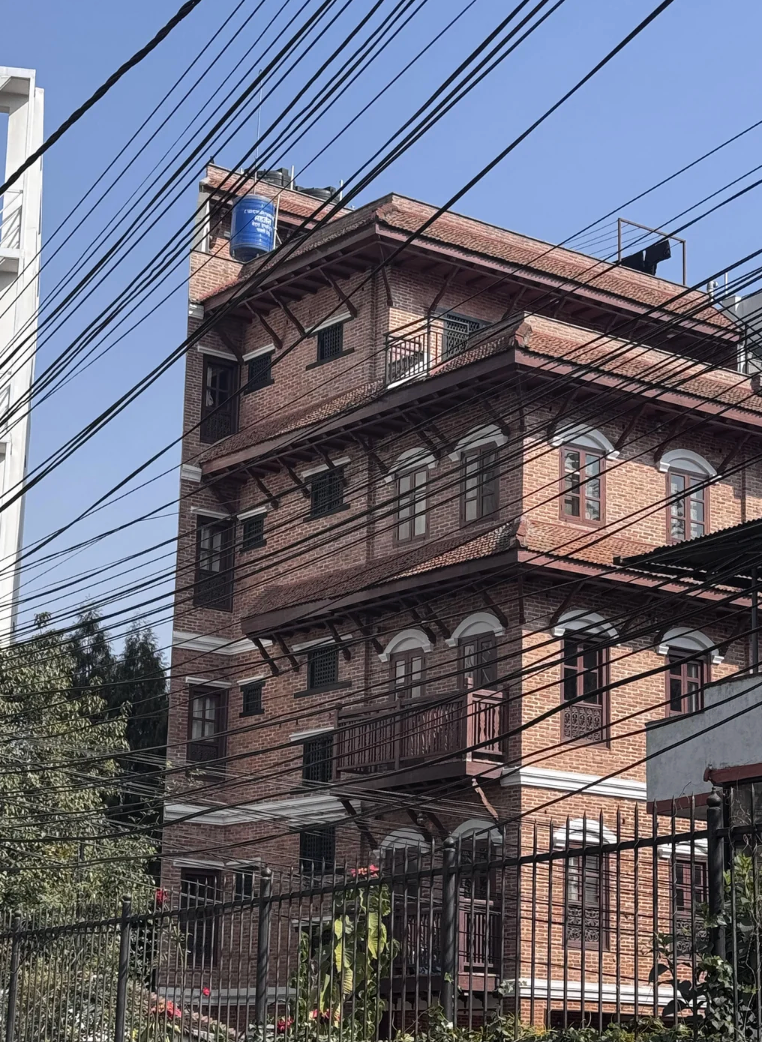 Multi-story ceramic  gathering  with balconies and a bluish  h2o  vessel  connected  the roof, intersected by galore   overhead wires