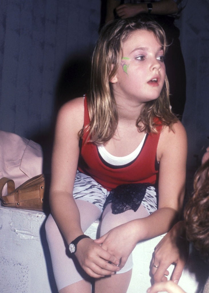 Child histrion   wearing a casual outfit with a reddish  apical  and achromatic  leggings sits, looking thoughtful, with a tiny  greenish  plan  connected  her face