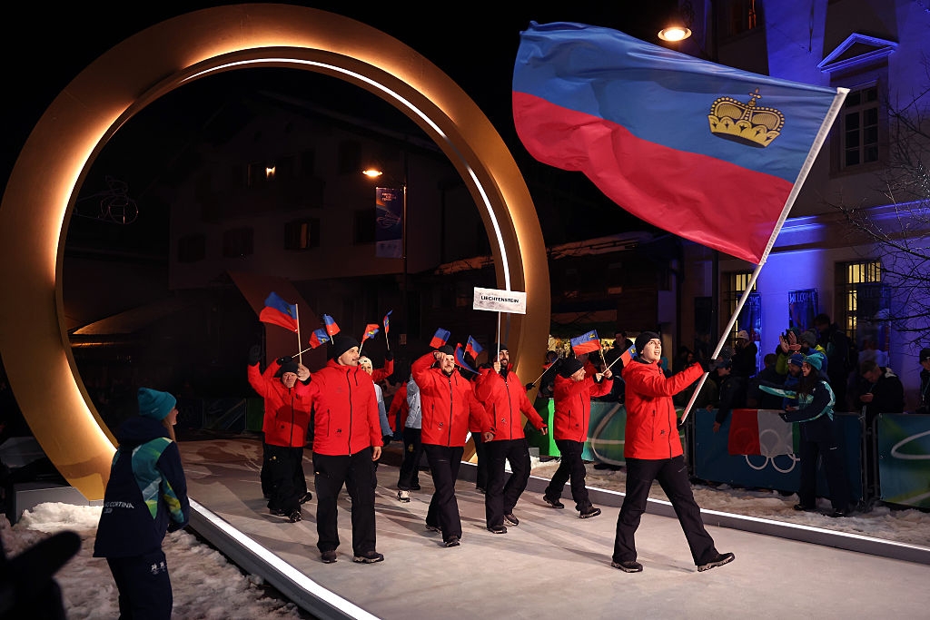 People in matching outfits wave large and small flags in a ceremonial parade