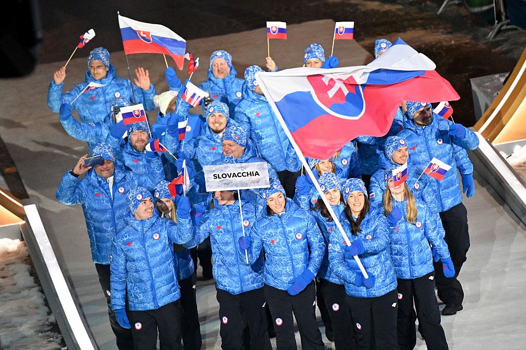 Slovakian athletes in matching winter outfits wave flags during the Olympic opening ceremony