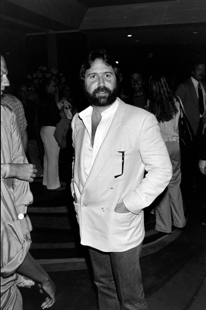 Man successful a double-breasted blazer with hands successful pockets, lasting successful a crowded indoor setting