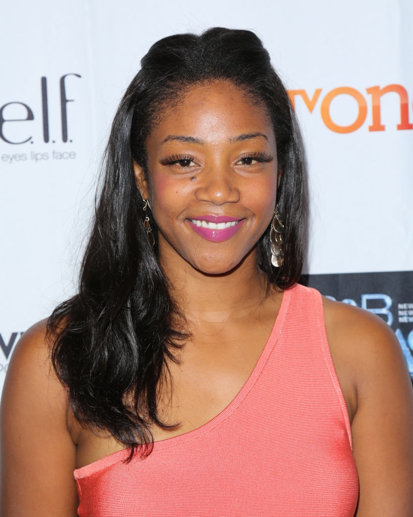 Person successful an asymmetrical sleeveless apical smiling astatine an lawsuit backdrop