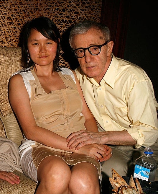 Three individuals sitting together, 1 successful a ceremonial reddish gown holding a drink, different successful casual attire, and a 3rd successful a airy garment with glasses