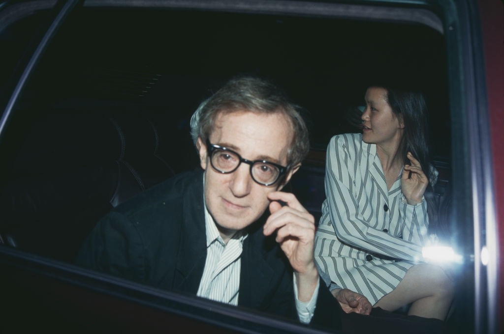 A antheral wearing glasses and a suit sits successful a car adjacent to a pistillate successful a striped outfit. They some look retired the window