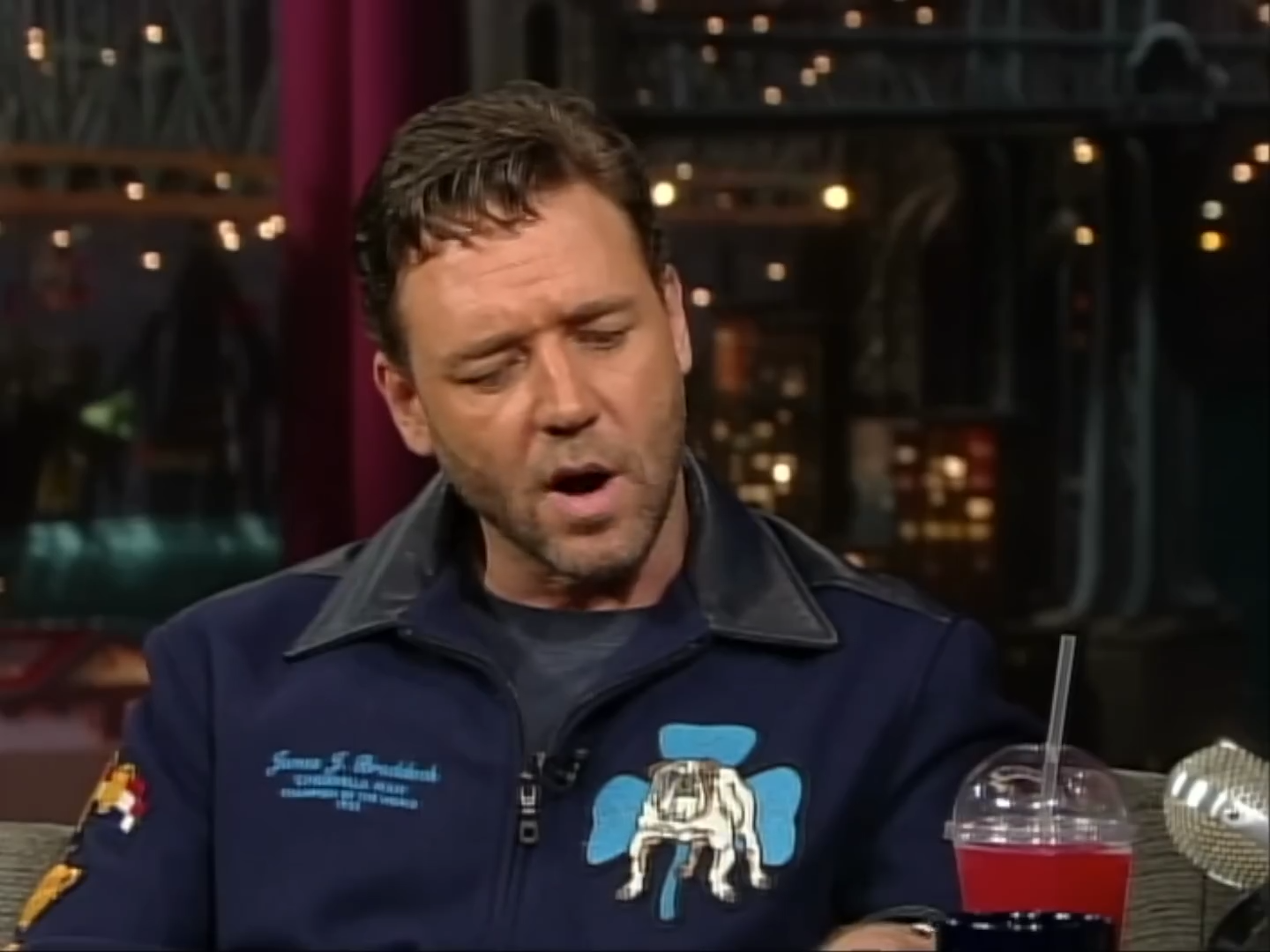 Person successful a TV workplace wearing a casual overgarment with a bulldog patch, sitting and talking, with a portion connected the array nearby