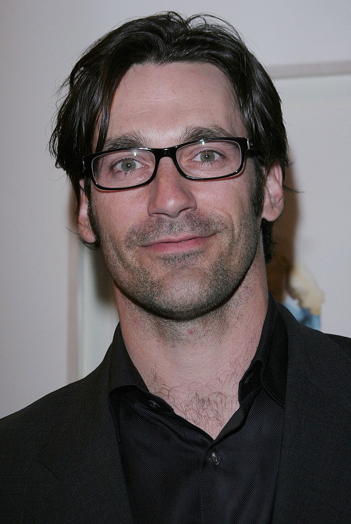 A idiosyncratic wearing glasses and a acheronian suit smiles astatine the camera