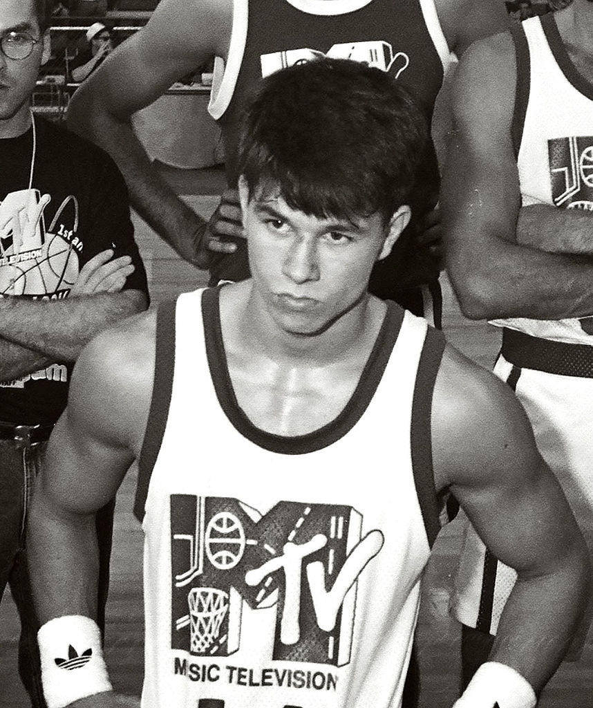 A young antheral successful a hoops jersey with "MTV" and sports graphics stands connected a court, focused and surrounded by others