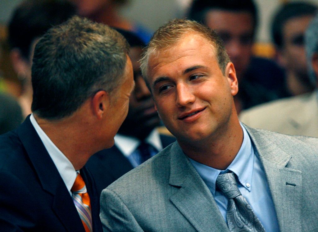 Two men successful suits, engaged successful conversation, seated astatine an event