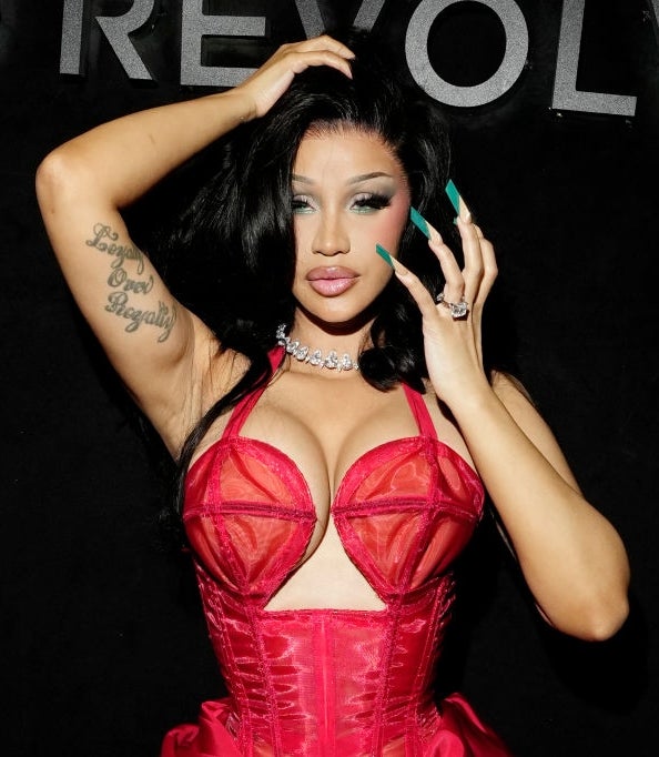 Person posing connected the carpet successful a bold, structured reddish formal with intricate details, accessorized with jewelry