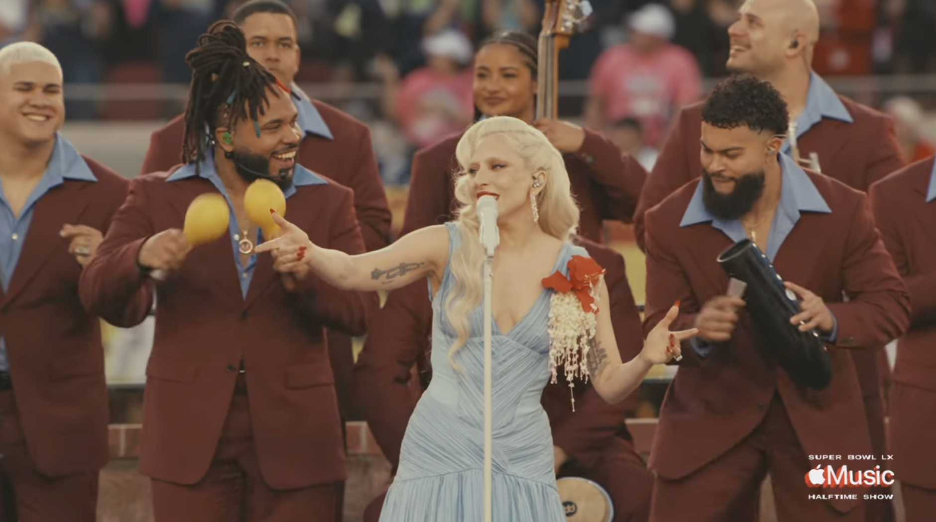 A vocalist  performs successful  a airy  dress, surrounded by a set  successful  suits, during a unrecorded  euphony  event