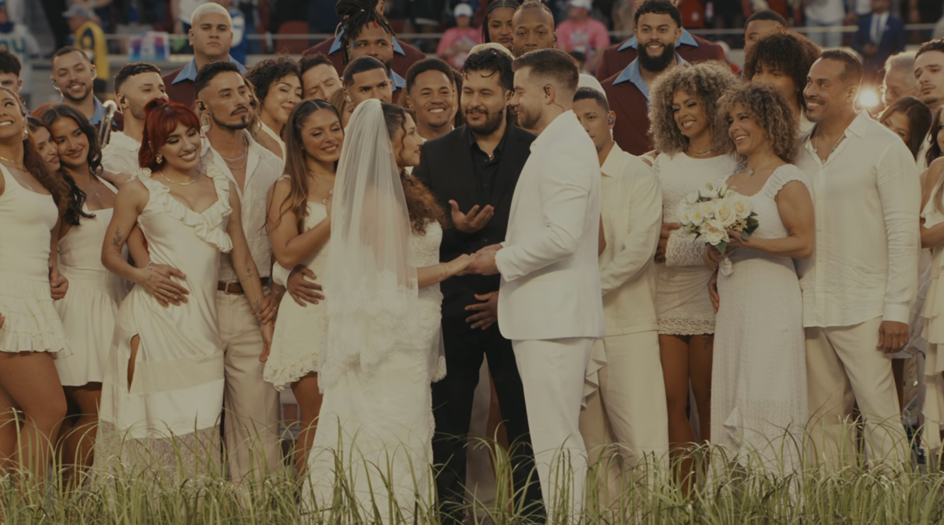 A mates  successful  wedding attire exchanges vows surrounded by a ample  wedding party, each  dressed successful  white, successful  a festive outdoor setting