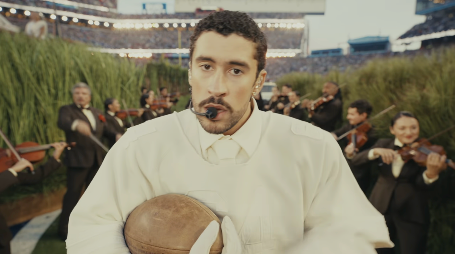 Performer successful  a shot   tract  holds a shot  and wears a achromatic  outfit. An orchestra plays successful  the inheritance  during the event