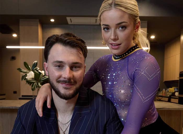 Two people sit at a table. One wears a pinstripe suit, holding a bowl of cereal, while the other leans on them in a sparkly gymnastics outfit
