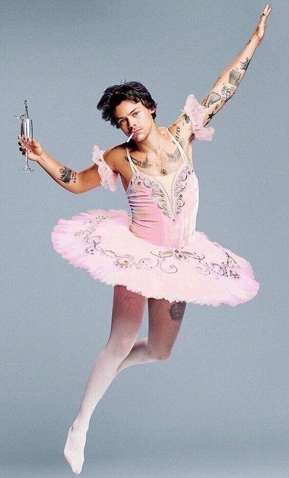 Persona con tutú decorado en pose de ballet, sujetando una copa. Lleva un cigarrillo en la boca y tiene varios tatuajes visibles