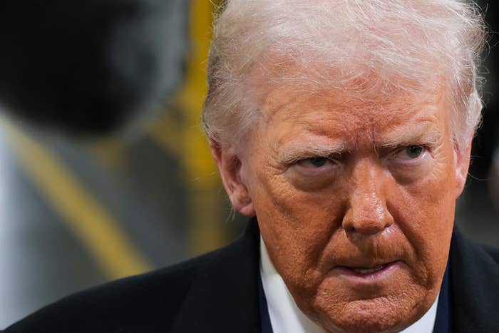 Man successful  a ceremonial  overgarment  and reddish  necktie  speaks portion    a ample  microphone is disposable   overhead successful  an indoor setting