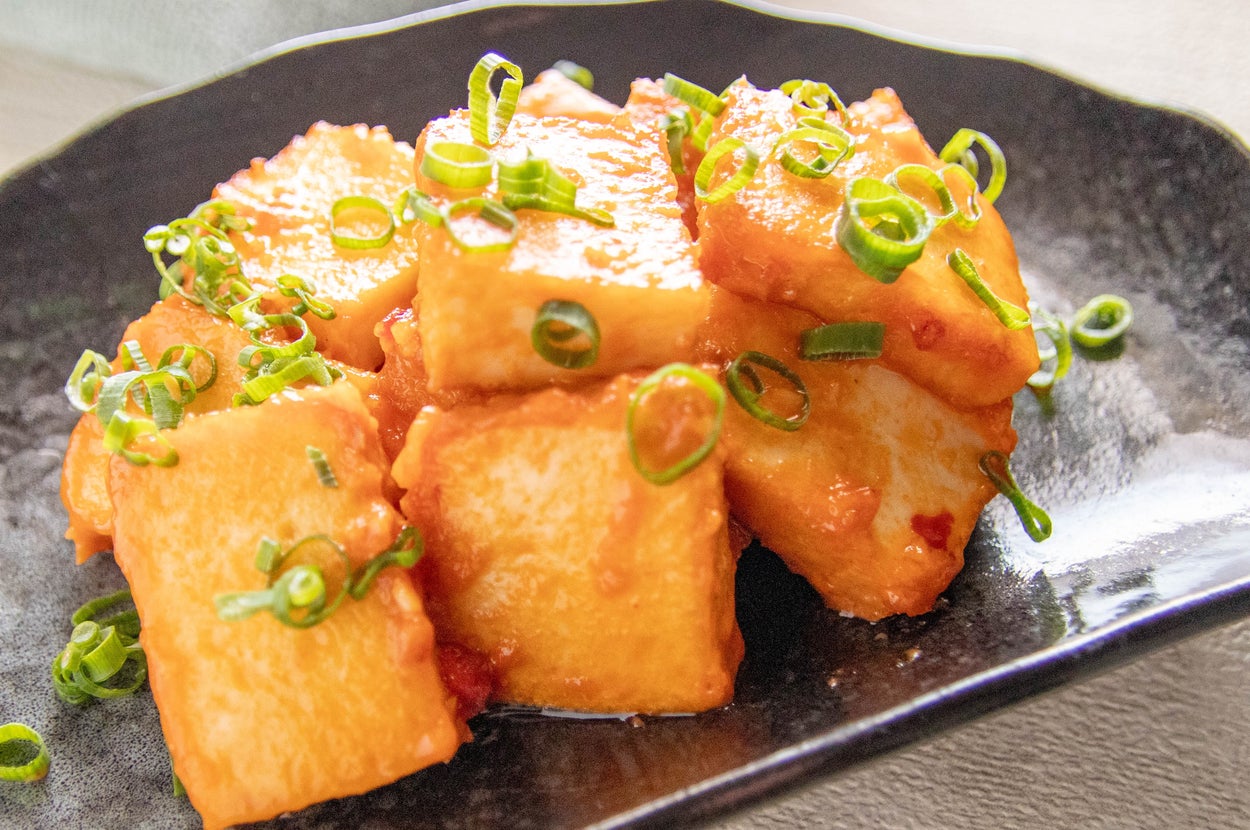 黒い皿に揚げた厚揚げ豆腐が盛られ、ネギが散らされています。