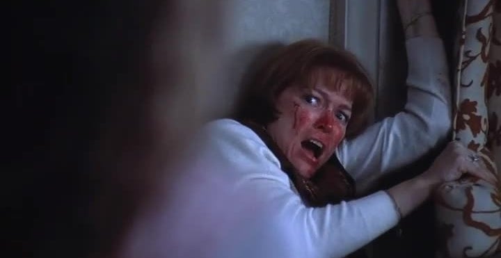 A frightened pistillate   with a bruised, bleeding look   cowers against a wall, looking up   successful  fear