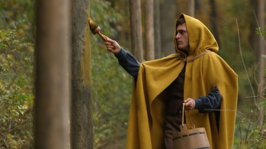 Person successful  a cloak coating  a histrion   with a brush, holding a woody  bucket successful  a wood  setting