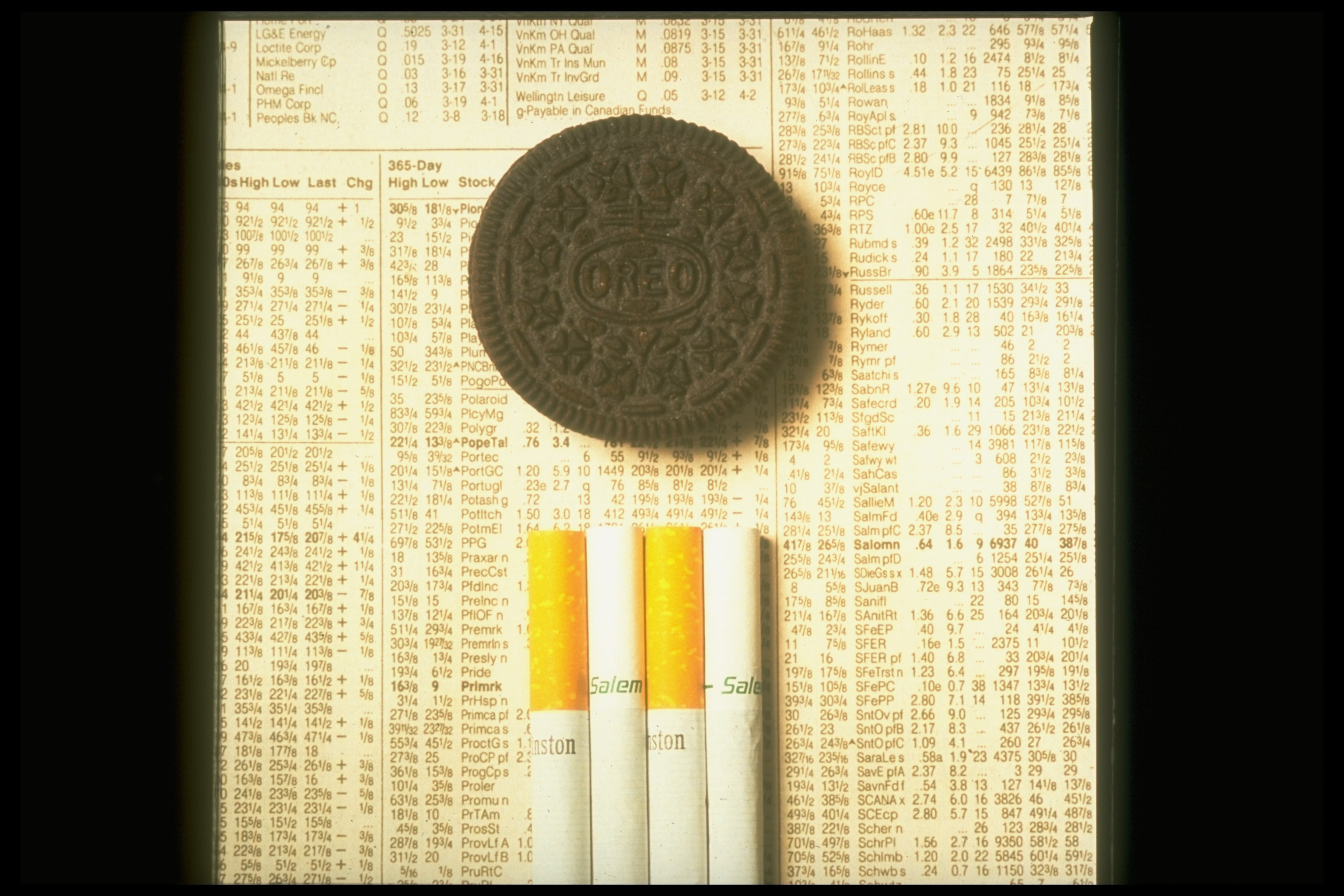 An Oreo cooky  and a enactment      of cigarettes are placed connected  a leafage   of banal  listings, juxtaposing acquainted  items with fiscal  data
