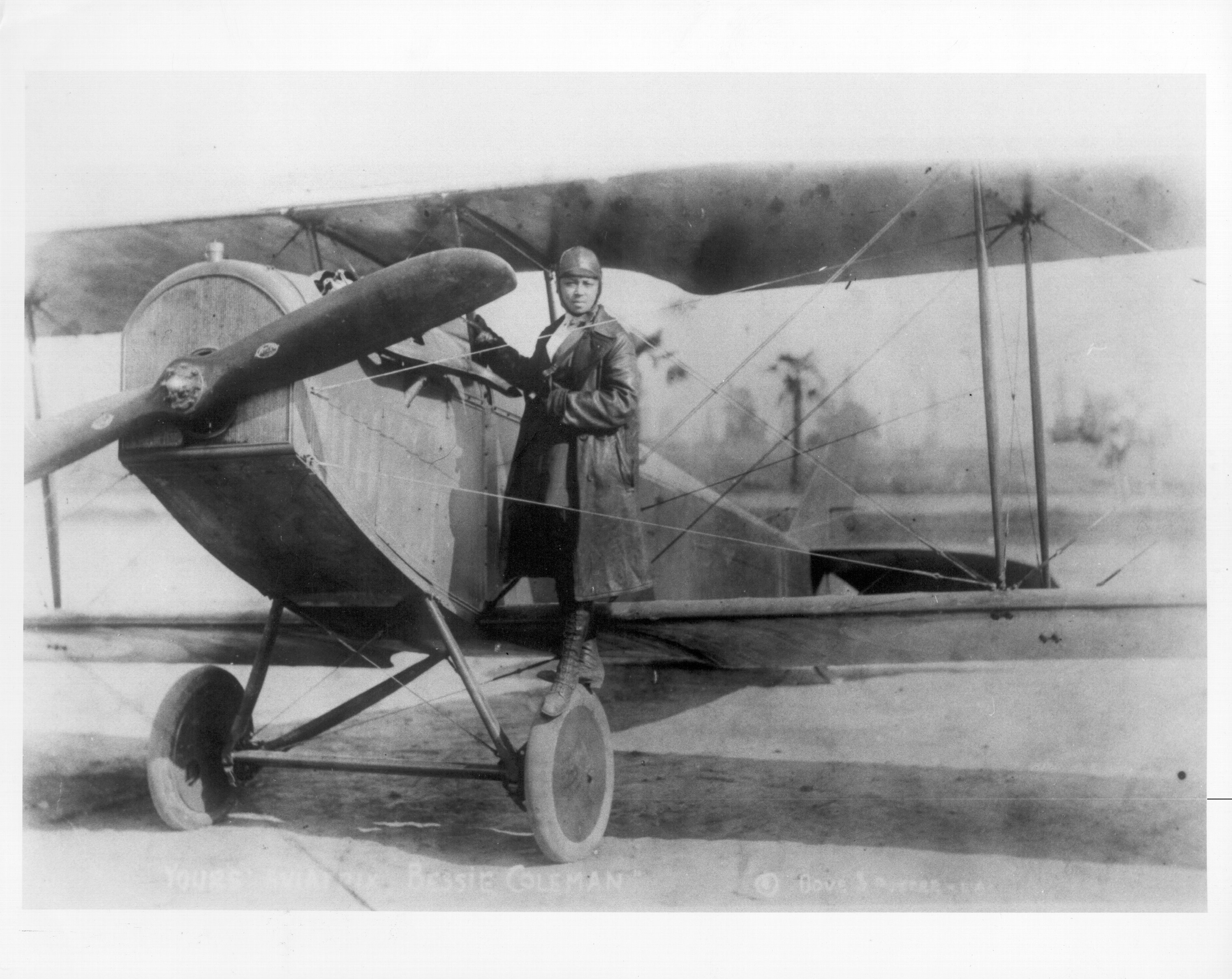 Vintage photograph  of a aviator  successful  aviation cogwheel  lasting  beside an aboriginal  biplane, evoking the aboriginal  20th-century epoch  of flight