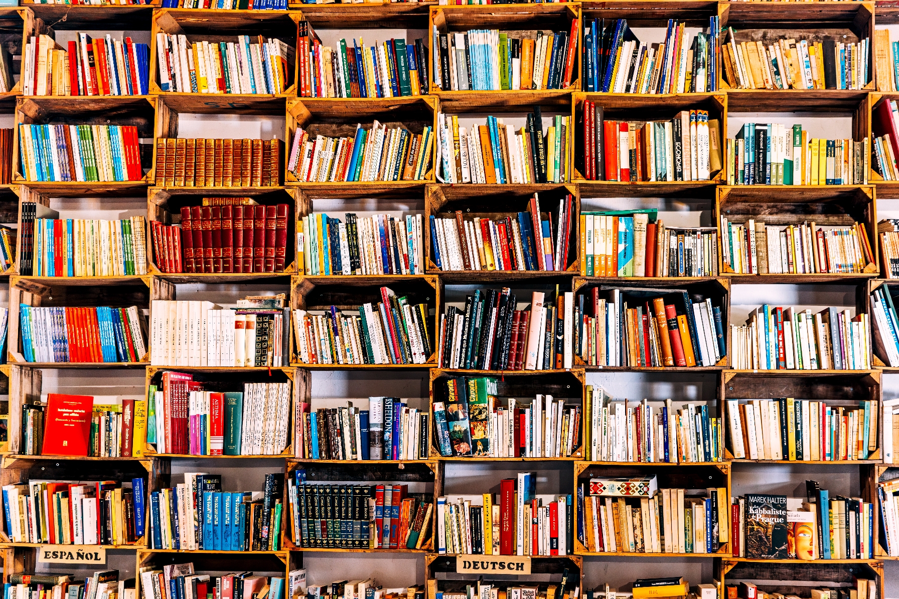 A bookshelf filled with various books in different languages organized in wooden crates