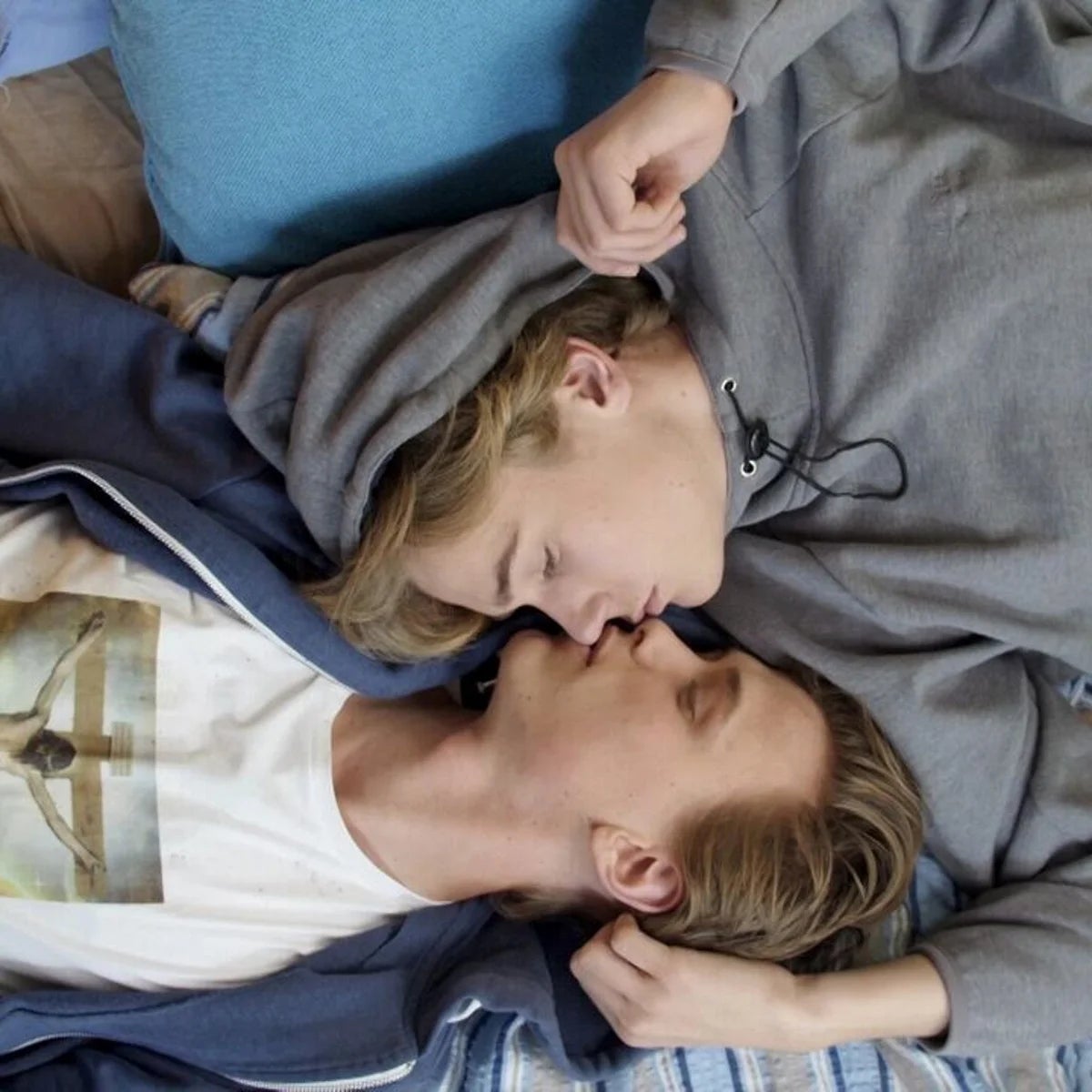 Dos personas acostadas mirándose; una lleva sudadera y la otra camiseta con imagen impresa