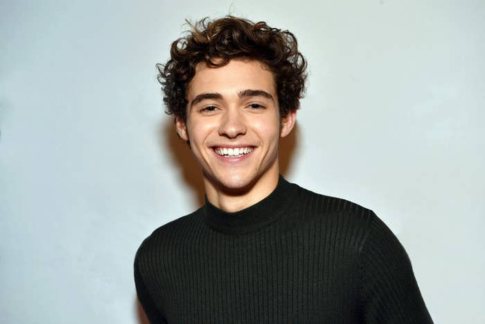 Celebrity wearing a ribbed sweater, smiling at the camera with curly hair styled casually