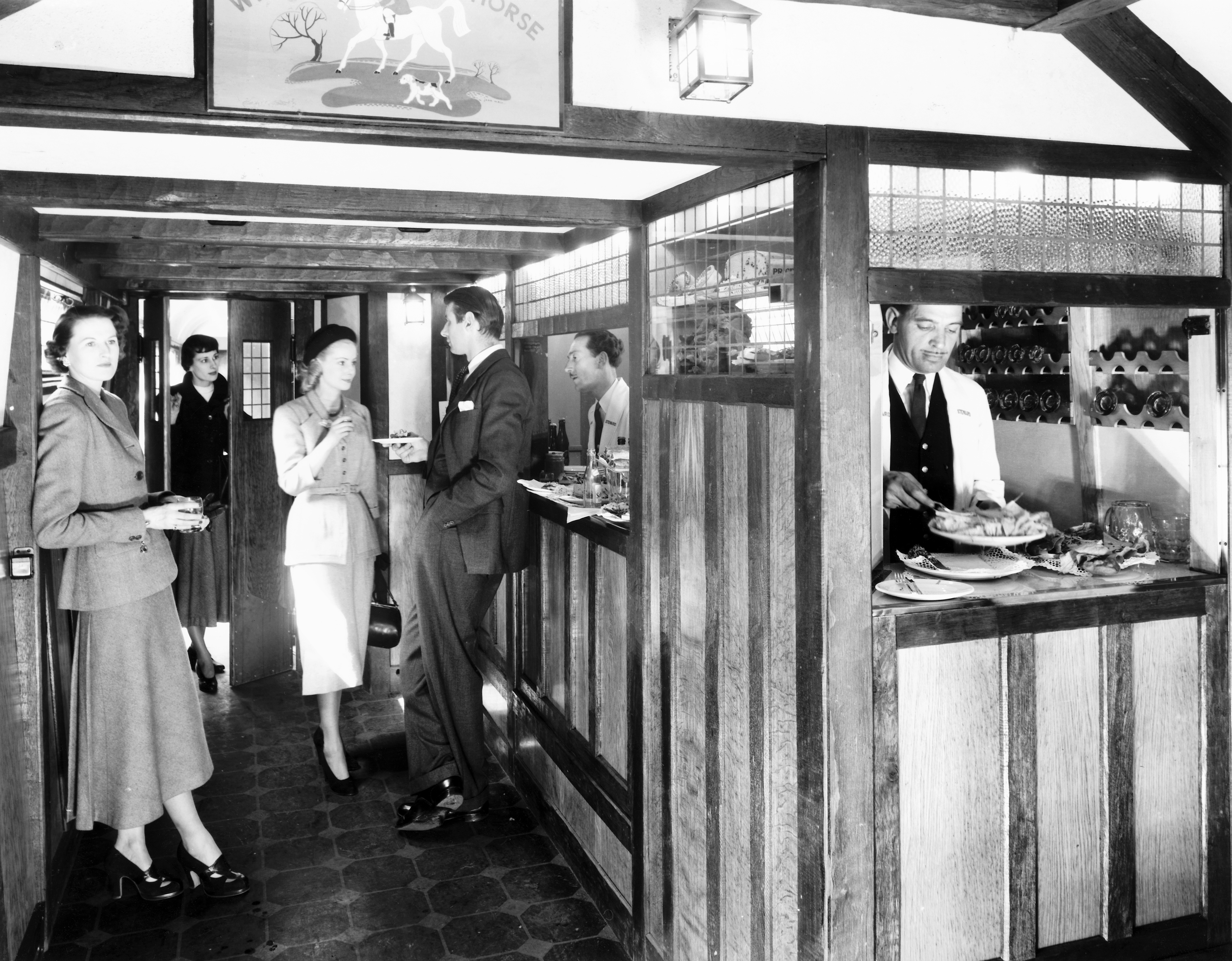 1940s country   successful  a wooden-paneled restaurant. People basal   chatting and eating. A server successful  a azygous   prepares nutrient  down  the counter
