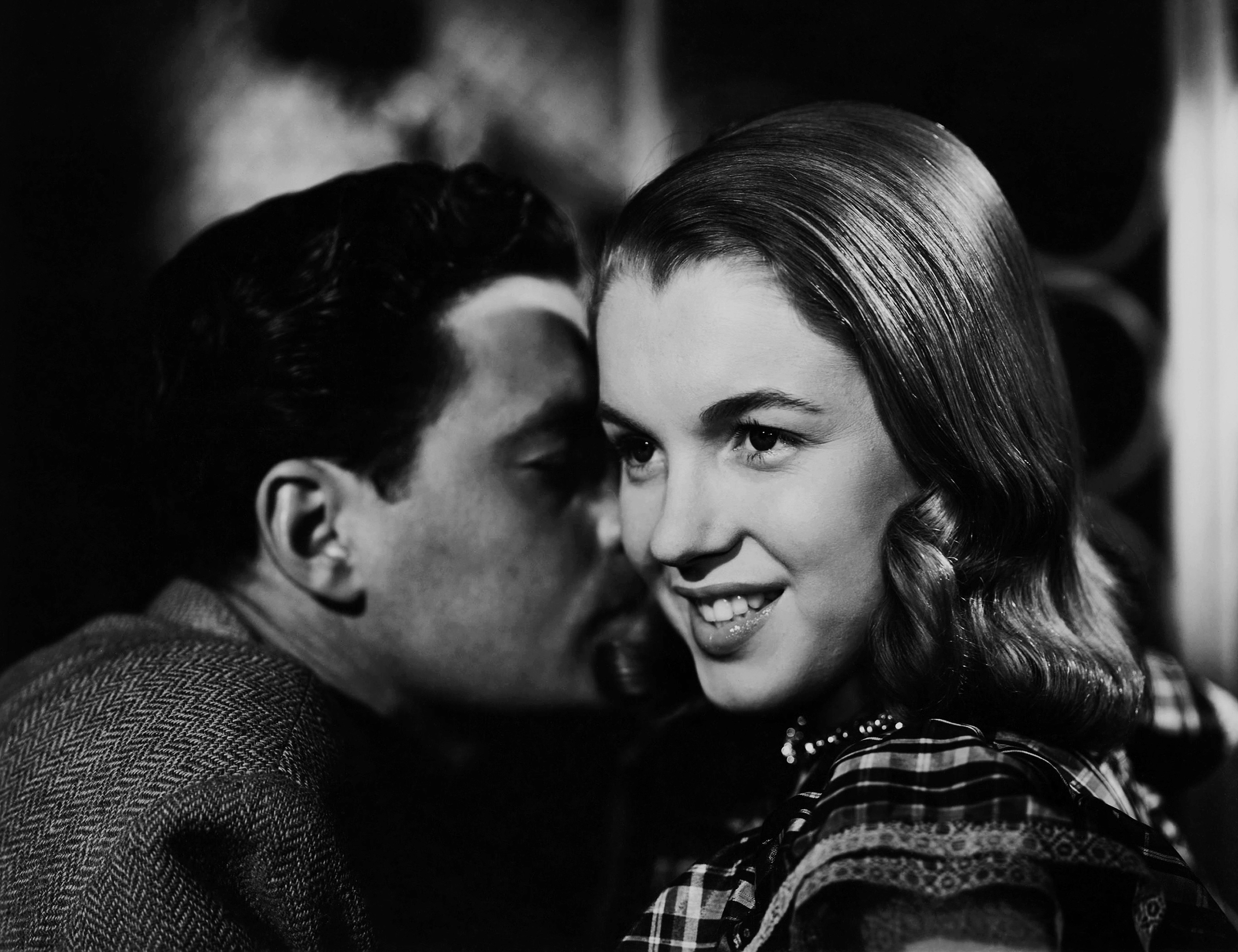 A idiosyncratic   whispers intimately  to a smiling pistillate   successful  vintage attire, creating a country   of intrigue and suspense