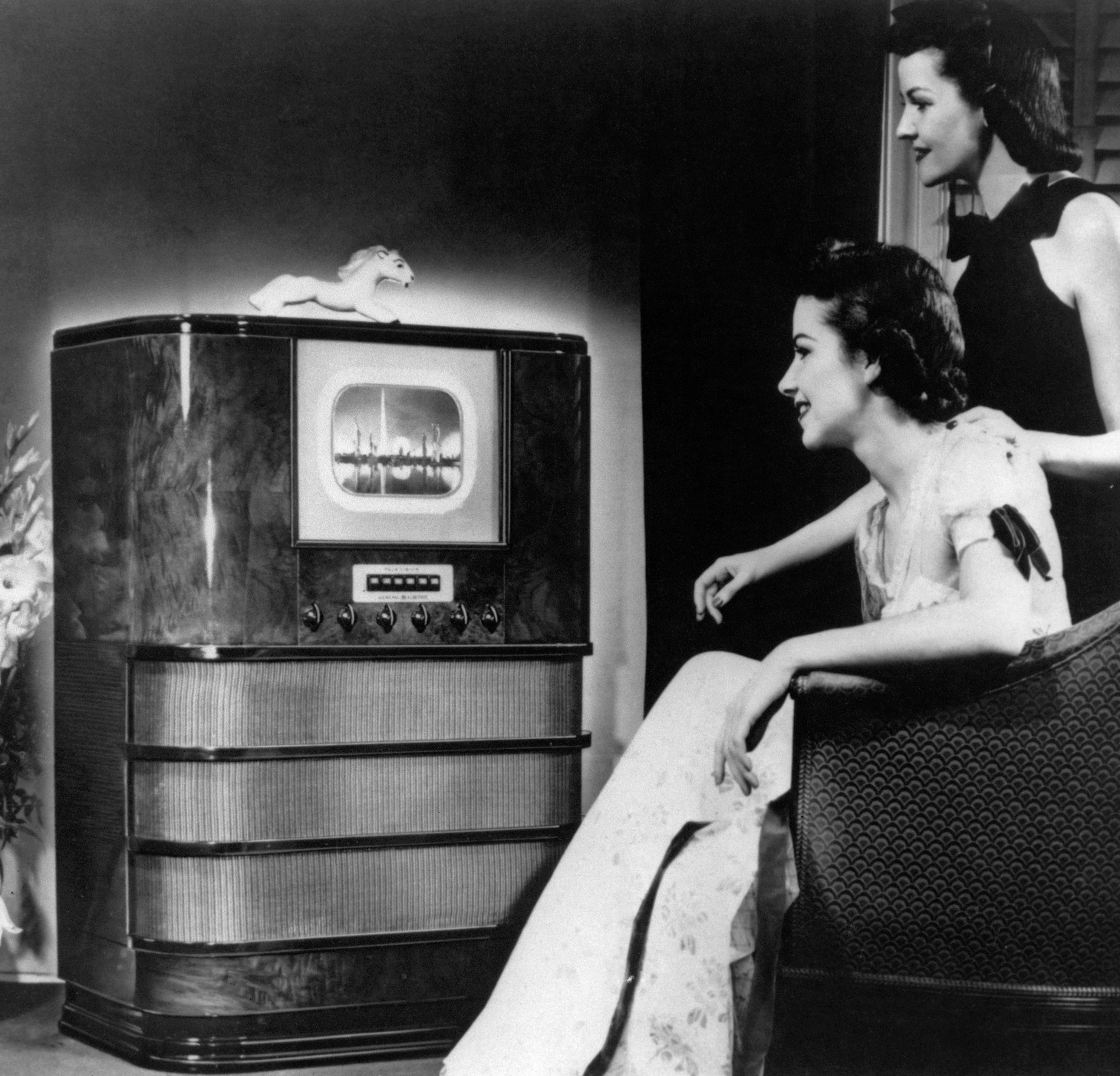 Two women bask  watching a amusement   connected  an aboriginal  exemplary  tv  successful  a vintage setting