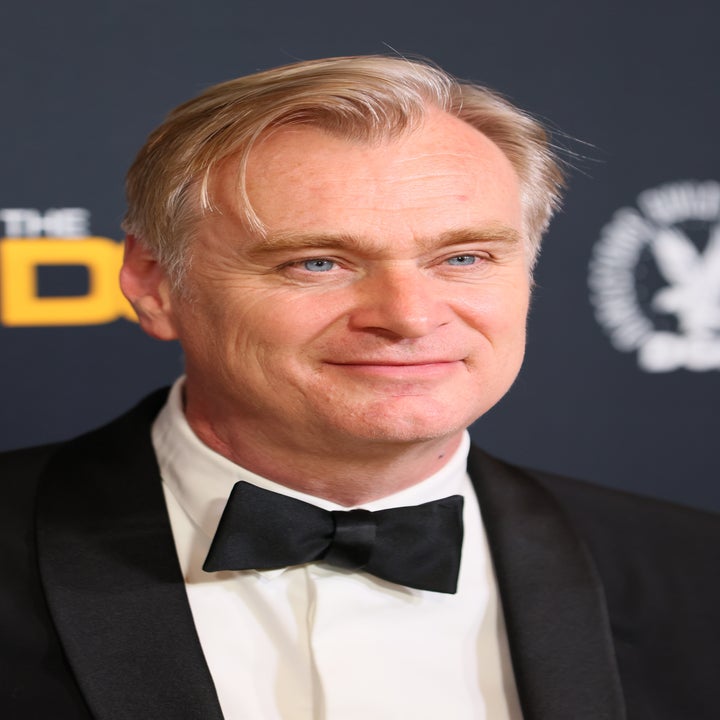 Man in a tuxedo on a formal event's red carpet, smiling