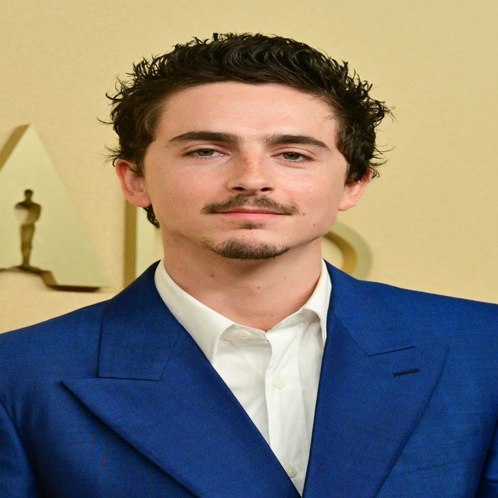 Person in a tailored suit with an open-collared shirt at a formal event